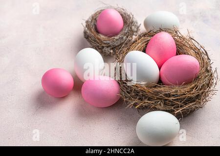 Happy Easter, a nest with white and pink Easter eggs on a delicate pastel background. Side view. Stock Photo