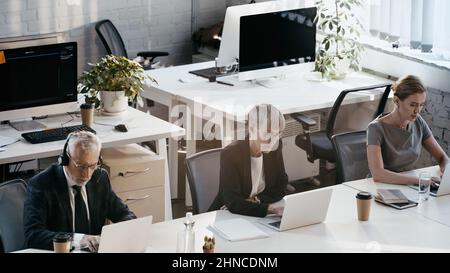 High angle view of business people using laptops near notebooks in office Stock Photo