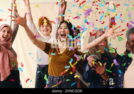 Action shot of mixed age range multi ethnic women celebrating International Women's Day with ticker tape Stock Photo
