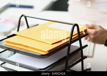 Businessman putting yellow envelope on holder for further delivery on address Stock Photo