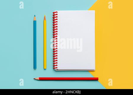 Spiral notebook with colored pencils and with copy space for your image or text over yellow and blue background Stock Photo