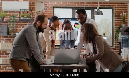 Team of workmates using laptop to plan business project in boardroom office. Colleagues working together on company growth and development to design marketing strategy and presentation. Stock Photo