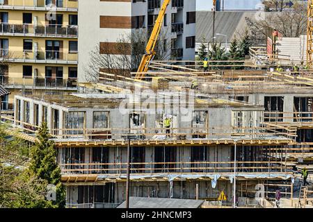 Construction workers install formwork and iron rebars or reinforcing bars for reinforced concrete partitions at residential building construction site Stock Photo