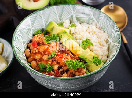 Chili con carne and couscous in bowl on dark background. Mexican cuisine. Stock Photo