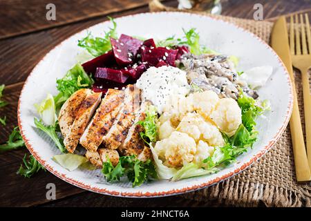 Healthy lunch. Boiled beetroot salad with greens, stewed mushrooms,  and grilled chicken fillet and baked cauliflower. Dinner. Stock Photo