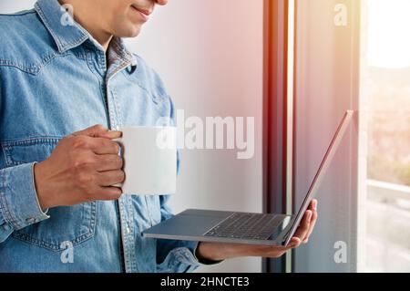 Shot of a handsome young businessman drinking coffee while working on a laptop in his home office Stock Photo