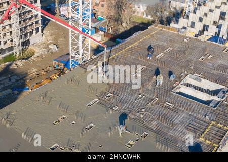 Pouring cement on the floors of residential multi-story building under construction using a concrete pump truck with high boom to supply the mixture t Stock Photo
