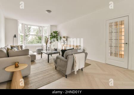 Interior of spacious living room with comfortable sofa and cushions placed on carpet near table and window in modern apartment