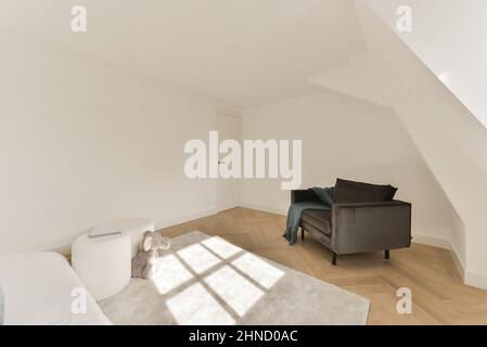 Interior of modern room in house furnished with comfortable sofa and bed and settee with cushions near poufs and plush toy on carpet Stock Photo