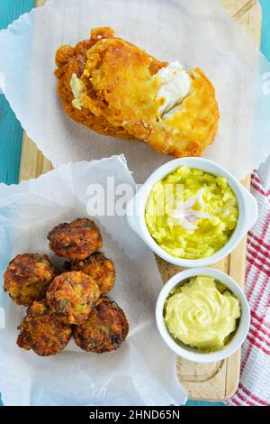 Fried cod fish fillets ,croquettes of cod fish served in parchment paper and mayonnaise and garlic dip served in bowls Stock Photo