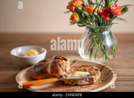 A toasted and buttered Hot Cross Bun, a sweet spiced bun traditionally eaten on Good Friday Stock Photo