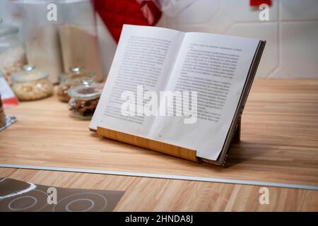 an open book in a stand on the kitchen table, storage jars, kitchen utensils. Stock Photo