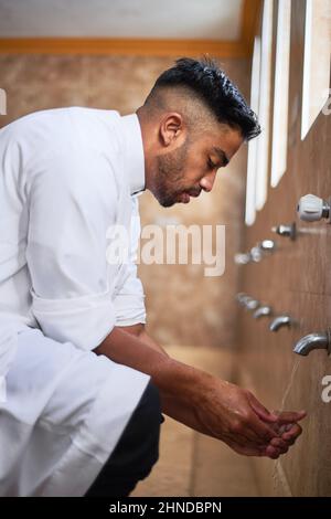 A young Muslim man cleansing his hands in the washroom  Stock Photo