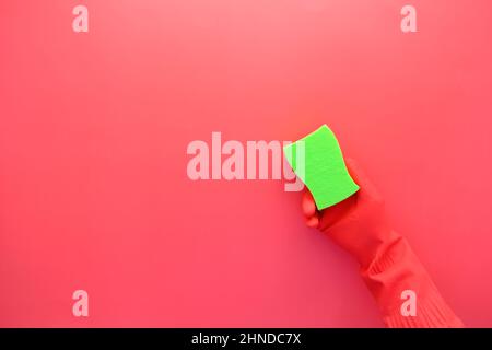 hand in rubber gloves holding a sponge on red background with copy space  Stock Photo
