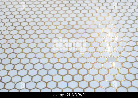 a white hexagon cermaic marble style tile floor with fold inlay grout Stock Photo