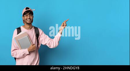 Cheerful middle eastern guy student pointing at copy space Stock Photo