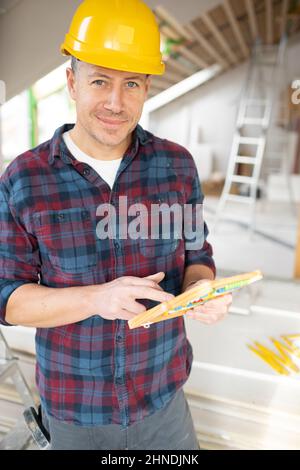 Construction worker with shirt and yellow helm calculates with abacus calculator on construction site in a loft Stock Photo