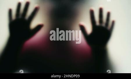 Depressed child concept stuck behind glass seeking help Stock Photo