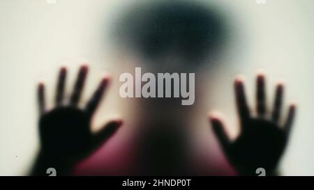 Depressed child concept stuck behind glass seeking help Stock Photo