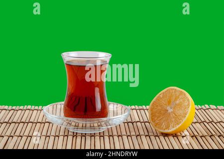 Glass of turkish tea and lemon on green background Stock Photo