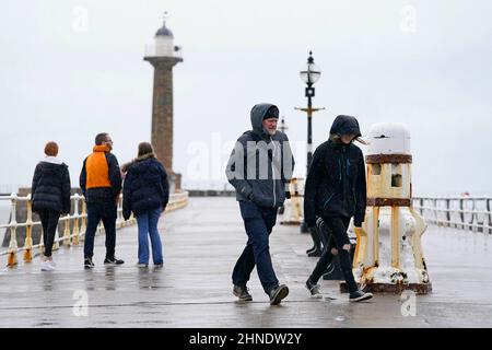 People walking in rainy conditions in Whitby, Yorkshire before Storm Dudley hits the north of England/southern Scotland from Wednesday night into Thursday morning, closely followed by Storm Eunice, which will bring strong winds and the possibility of snow on Friday. Picture date: Wednesday February 16, 2022. Stock Photo