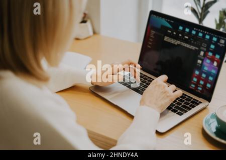 Mature adult woman hands, sitting in cafe with coffee mug and working online on laptop. Businesswoman typing on notebook computer in coworking space Stock Photo