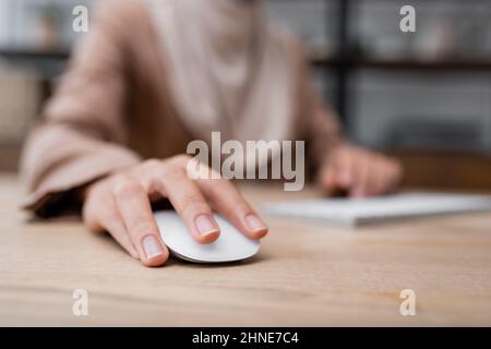 selective focus of computer mouse in hand of cropped woman working on blurred background Stock Photo