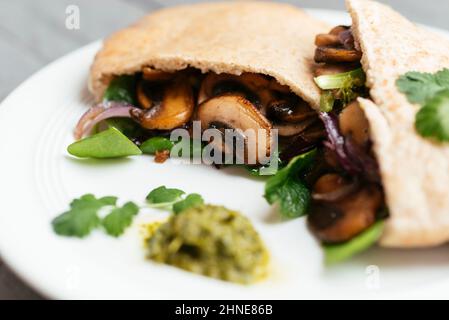 Pita breads filled with sauteed mushrooms and onions with winter purslane and corn salad, served with zhoug.