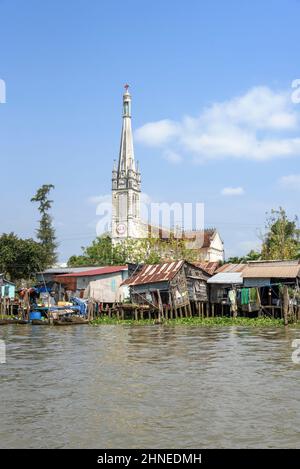 Riverside church and houses on wooden stilts on the Mekong River at Cai Be, Tien Giang Province, Mekong Delta, southern Vietnam, Southeast Asia Stock Photo