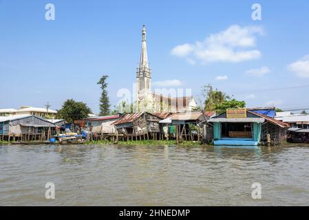 Riverside church and houses on wooden stilts on the Mekong River at Cai Be, Tien Giang Province, Mekong Delta, southern Vietnam, Southeast Asia Stock Photo