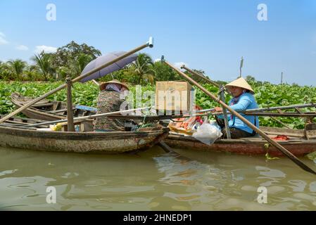 Vietnamese women with traditional wooden rowing / motor boats (sampans) on the Mekong River, Mekong Delta, Vinh Long Province, southern Vietnam Stock Photo
