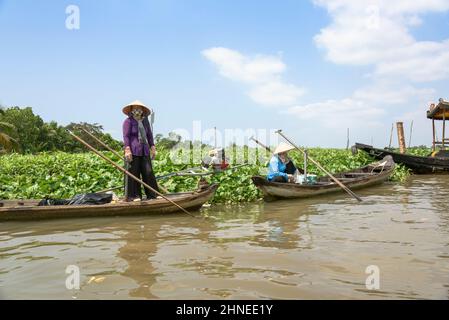 Vietnamese women with traditional wooden rowing / motor boats (sampans) on the Mekong River, Mekong Delta, Vinh Long Province, southern Vietnam Stock Photo