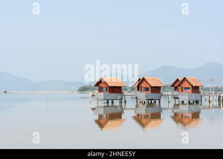 Wooden huts on stilts are reflected in the calm waters of Lap An Lagoon, Lang Co Bay, Phu Loc district, Thua Thien Hue province, central Vietnam Stock Photo