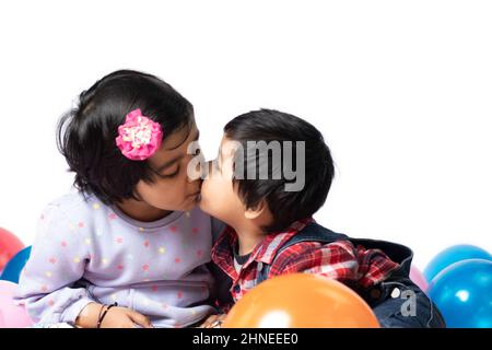 Asian Indian Elderly Sister Kisses Toddler Brother. Siblings, Love, Trust, Affection, Care, Companion, Innocence, Fun, Enjoyment, Tenderness, Together Stock Photo