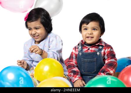Asian Indian Girl And Boy Playing With Balloons. Fun, Activity, Educational, Kindergarten, Birthday, Learning, Home Activity, School, Nursery, Daycare Stock Photo