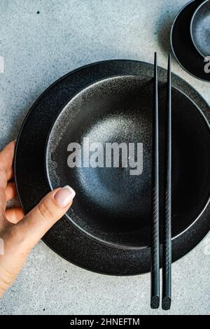 Overhead view of a woman laying a table with Asian tableware Stock Photo