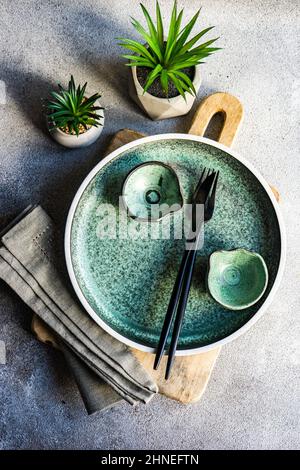 Minimalistic table setting on a chopping board with two houseplants Stock Photo