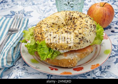 bagel with salmon in a plate on a table with an apple Stock Photo