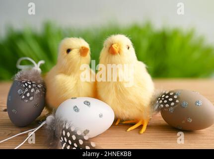 Easter composition with Colorful Easter eggs, chicks on green grass and grey background. Easter concept. Stock Photo