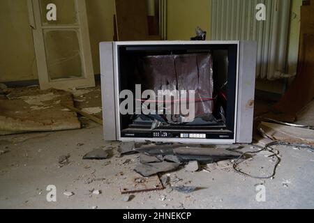 old TV with broken CRT display in a guests room of an abandoned sanatorium, Germany Stock Photo