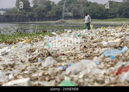 A man collects discarded plastic items on the banks of the river Buriganga, in Dhaka, Bangladesh, February 16, 2022. Industrial waste and sewage from the city are all dumped into the rivers. The once fresh and flowing rivers like Buriganga, is now submerged in pollution. The other rivers of the country face the same fate. Recent research has brought an even more horrendous picture into view. And that is plastic pollution. In just the four rivers that surround the capital city Dhaka, 30,000 tonnes of plastic waste were discovered. Half of this was in the river Buriganga. (Photo by Suvra Kanti D Stock Photo