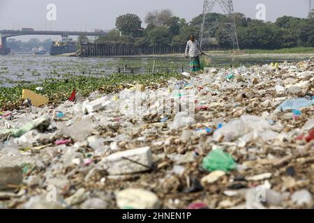 A man collects discarded plastic items on the banks of the river Buriganga, in Dhaka, Bangladesh, February 16, 2022. Industrial waste and sewage from the city are all dumped into the rivers. The once fresh and flowing rivers like Buriganga, is now submerged in pollution. The other rivers of the country face the same fate. Recent research has brought an even more horrendous picture into view. And that is plastic pollution. In just the four rivers that surround the capital city Dhaka, 30,000 tonnes of plastic waste were discovered. Half of this was in the river Buriganga. (Photo by Suvra Kanti D Stock Photo