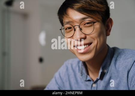 Cheerful asian guy in eyeglasses smiling while working in office Stock Photo