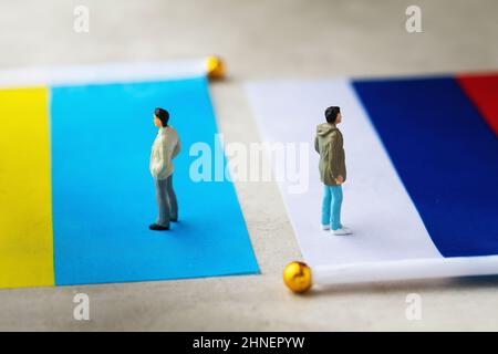 Toy people made of plastic and two flags on an abstract background, a concept on the theme of relations between Russia and Ukraine Stock Photo