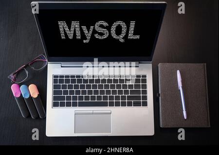 Top view of laptop with text MySQL. MySQL inscription on laptop screen and keyboard. Learn MySQL language, computer courses, training. Stock Photo