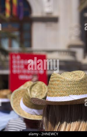 Close-up of an unrecognizable woman in the audience at an outdoor event where everyone is wearing a straw hat to protect themselves from the sun Stock Photo