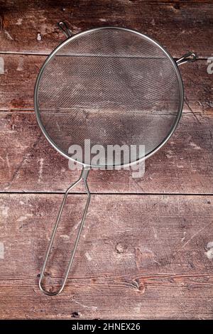 Wooden kitchen table with a stainless steel sieve strainer, baking concept Stock Photo