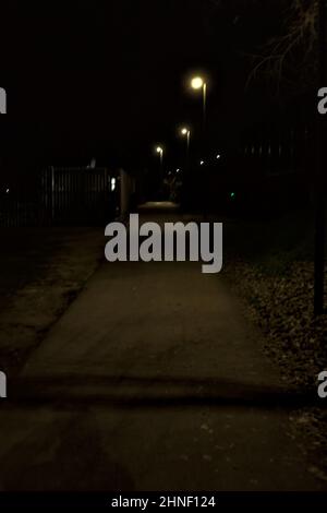 Gravel path lit by street lamps in a park at night seen from above ...