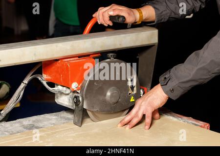 The master cuts a tile on an industrial machine with a diamond blade. Stock Photo