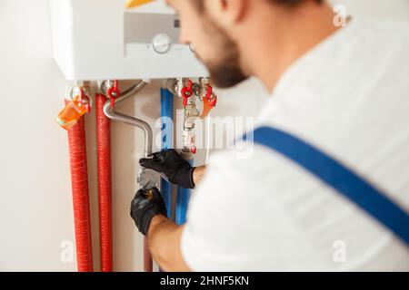 Closeup of plumber working with water pipes while installing heating system in apartment Stock Photo
